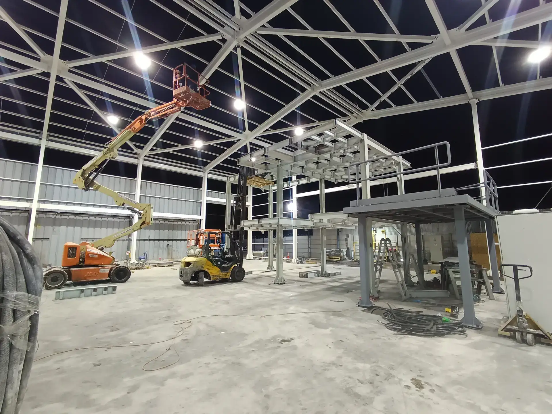 Montaje nocturno de estructura metálica con grúa elevadora